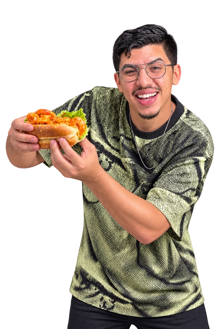 Mohammed Amine souriant, tenant un sandwich aux crevettes dans sa cuisine